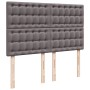 Graues Boxspringbett Kopfteil mit Knopfheftung und Holzfüßen.