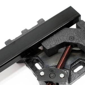 Wiltec Winkelschraubstock aus Gusseisen spannt schwarzes Metallprofil für präzise 90°-Winkelarbeiten.