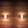 Zwei Philips LED-Außenwandleuchten Python aus Edelstahl mit Bewegungsmelder an Holzwand.