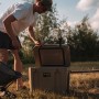 Petromax Kühlbox 25 l in Sand mit Person beim Öffnen im Outdoor-Einsatz.