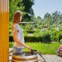 Frau bedient Gardena Akku-Regenfasspumpe 2000/2 zur Gartenbewässerung mit Regner.