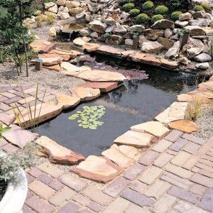Ubbink GFK-Fertigteich Venus 650 l im Garten mit Steinen und Pflanzen.