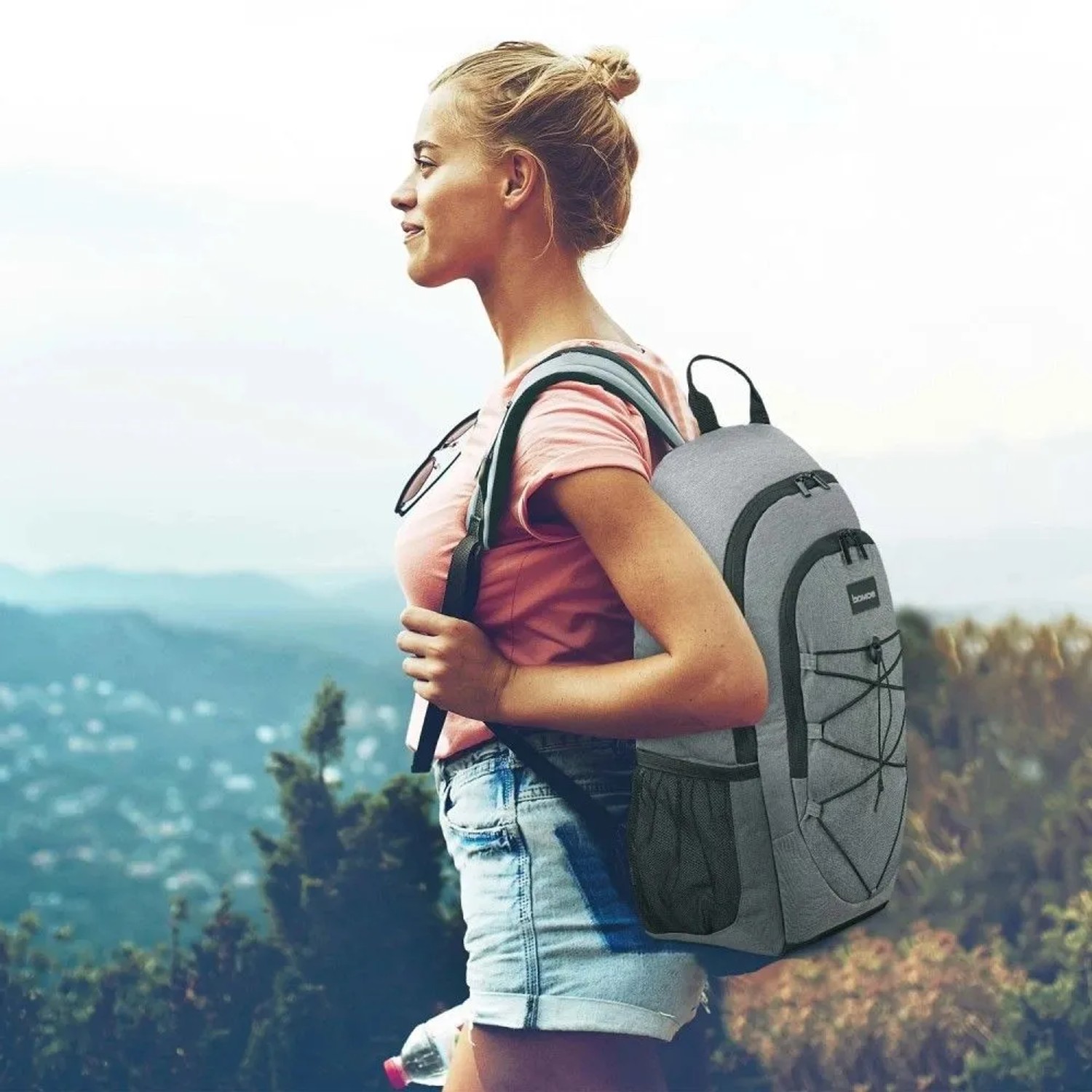Grauer Bomoe IceBreezer Kühlrucksack (25L) mit Trägern vor Landschaft.