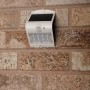 Weiße LED Solar-Außenleuchte mit Sensor an einer Backsteinwand. Flutlicht mit 220 Lumen.