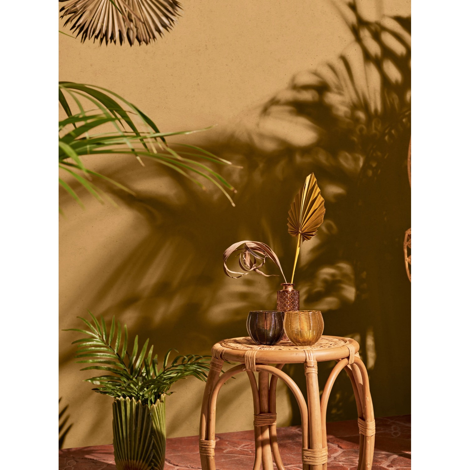 Gelber Teelichthalter Safari Lodge aus Glas, 8x9cm, auf Rattanhocker mit Deko.