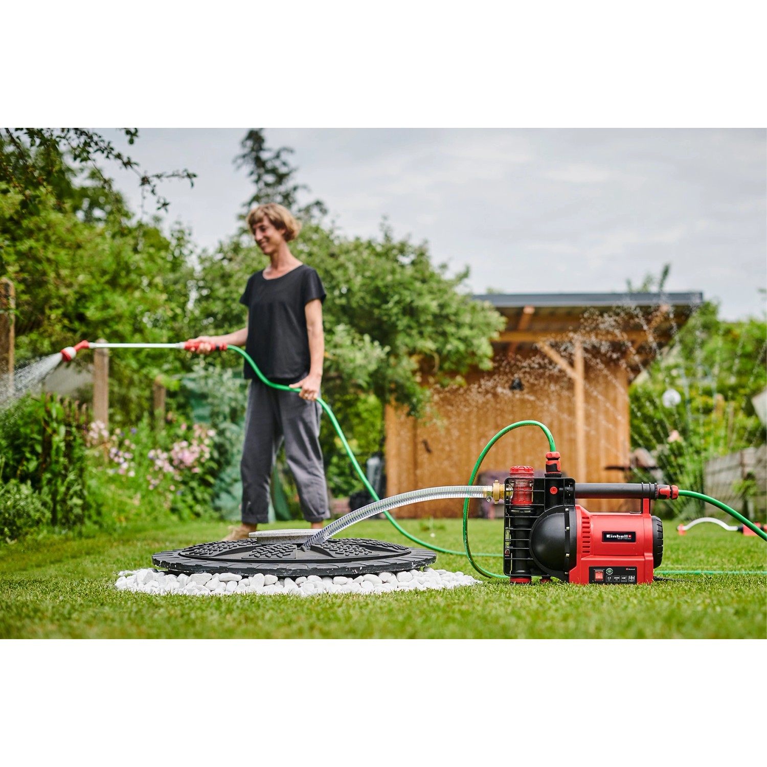 Einhell Gartenpumpe GE-GP 1246 im Einsatz: Frau bewässert Garten mit der Elektro-Pumpe.