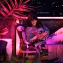 Frau entspannt im Garten, beleuchtet mit Philips Hue Lily LED-Spot in Farbe. Smarte Gartenbeleuchtung.