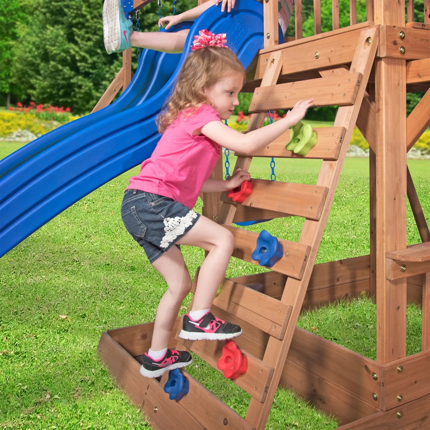 Kind klettert auf Spielturm Northbrook mit Rutsche und Kletterwand aus Zedernholz.