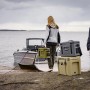 Petromax Kühlbox kx25 in Sand, gestapelt mit anderen Kühlboxen am See, transportbereit für Camping oder Ausflug.
