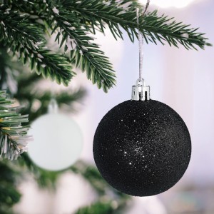 Glitzernde schwarze Weihnachtskugel aus Kunststoff am Tannenbaum. Teil des bruchsicheren Schwarz-Weiß 30er Sets.