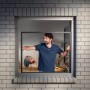 Mann montiert weißen tesa® Insect Stop Falt Alu-Rahmen Insektenschutz am Fenster.