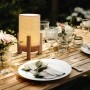 Näve LED-Tischleuchte Madita mit Leinen-Schirm und Holzfuß auf gedecktem Tisch.
