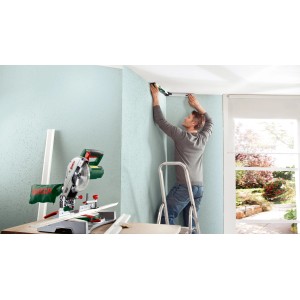 Mann misst Winkel mit Bosch UniversalAngle Winkelmesser an Wand, Kapp- und Gehrungssäge im Vordergrund.