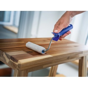 LUX Lasurwalze 12cm in Aktion: Weiße Mikrofaserwalze mit blauem Griff beim Auftragen von Lasur auf Holz.