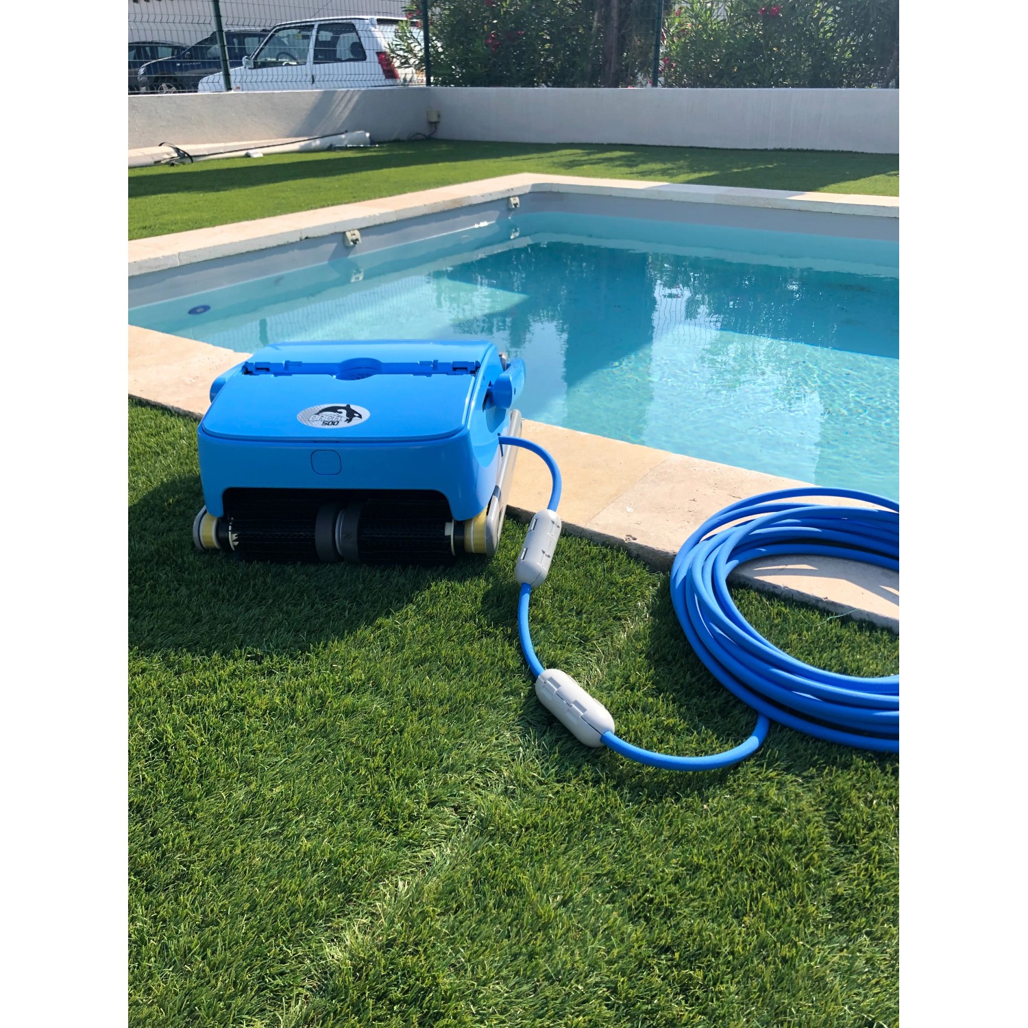 Summer Fun Orca 500 Poolroboter neben Pool auf Rasen mit Kabel.