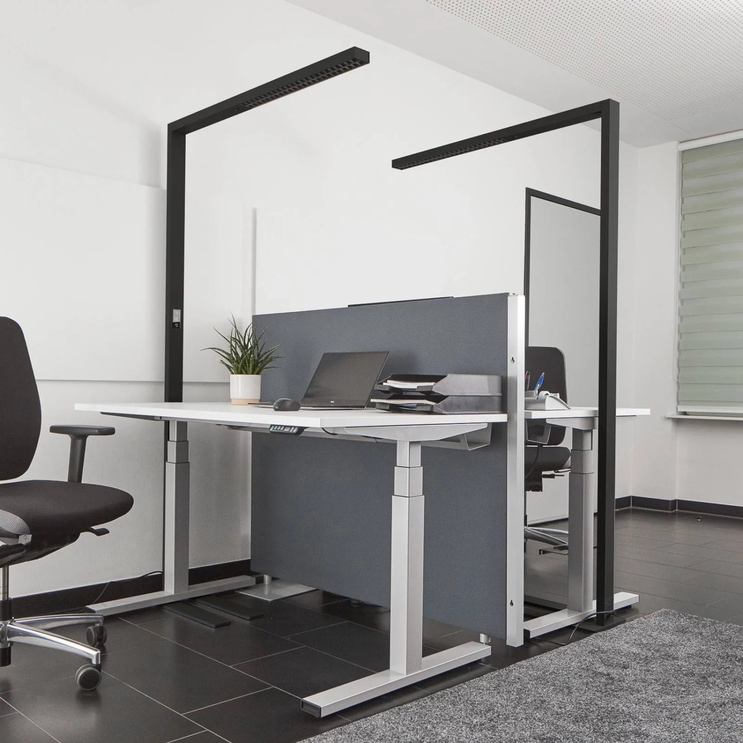 Moderne, dimmbare Arcchio LED Bürostehleuchte Jolinda in Schwarz über Schreibtischen im Büro.