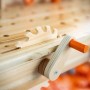 Nahaufnahme einer OBI Kinderwerkbank aus Holz mit Spielzeug-Säge und orangefarbener Kurbel.
