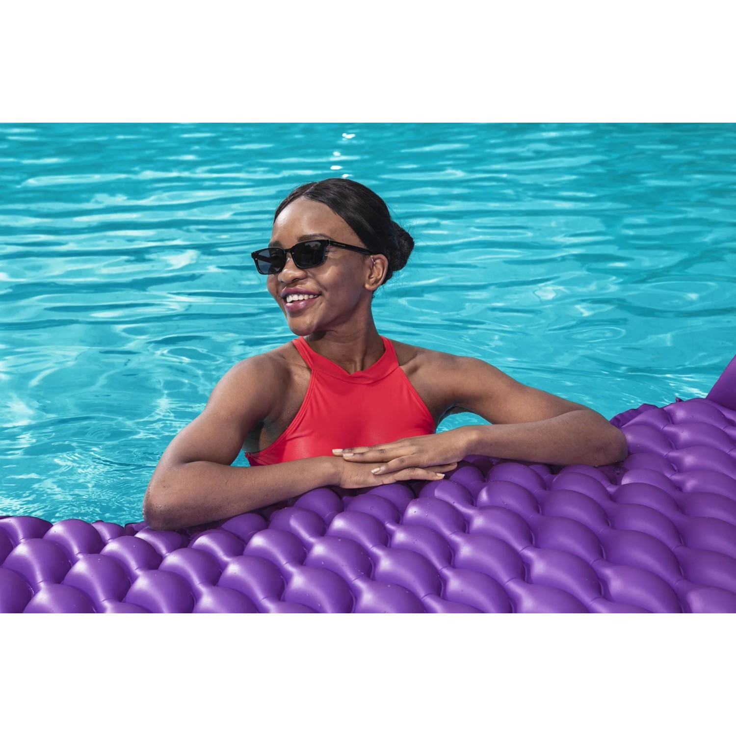 Frau entspannt auf lila Bestway Luftmatratze Float'n Roll im Pool.