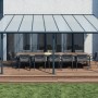 Graue Palram Canopia Terrassenüberdachung Sierra 555x295 cm mit Tisch und Stühlen.