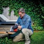 Mann sägt Holz mit der roten Einhell Handkreissäge TC-CS 1250 im Garten.