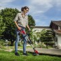 Frau trimmt Rasen mit dem roten Einhell Akku-Rasentrimmer GE-CT 18 Li Kit Power X-Change.