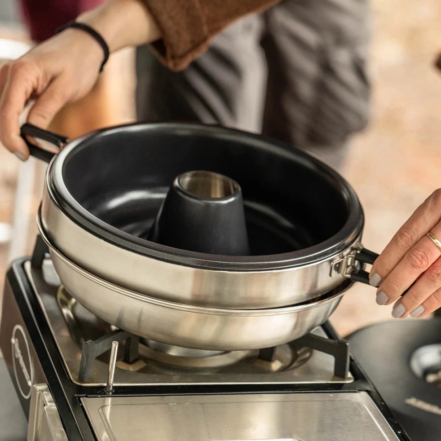 Petromax Camping-Backofen Dimego 2 l auf Gaskocher, mit Händen gehalten. Ideal für Outdoor-Küche.