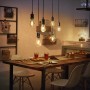 Esstisch mit mehreren, von der Decke hängenden Philips Hue Filament E27 LED-Lampen.