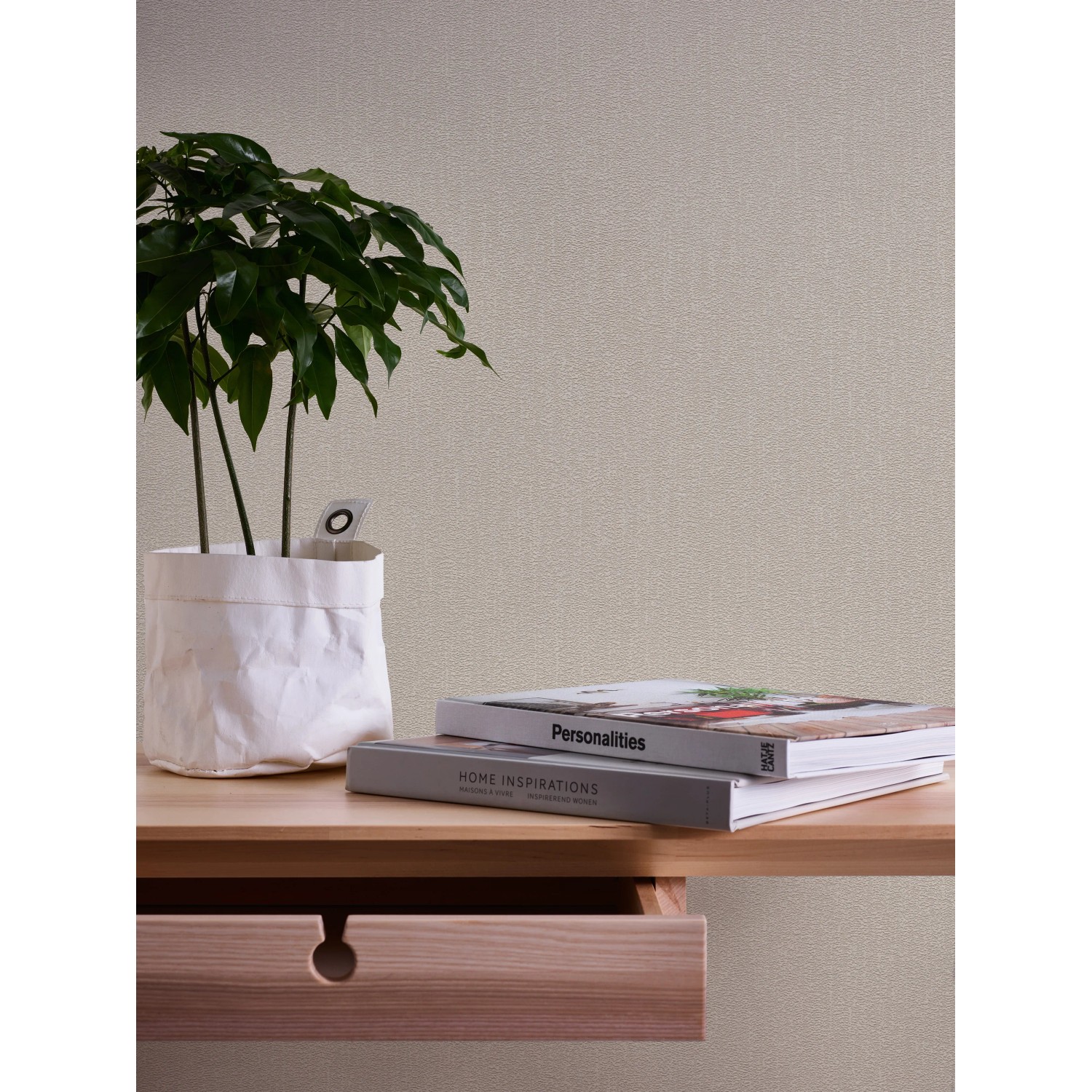 A.S. Création Vliestapete Uni Beige an Wand, kombiniert mit Tisch, Pflanze und Büchern.