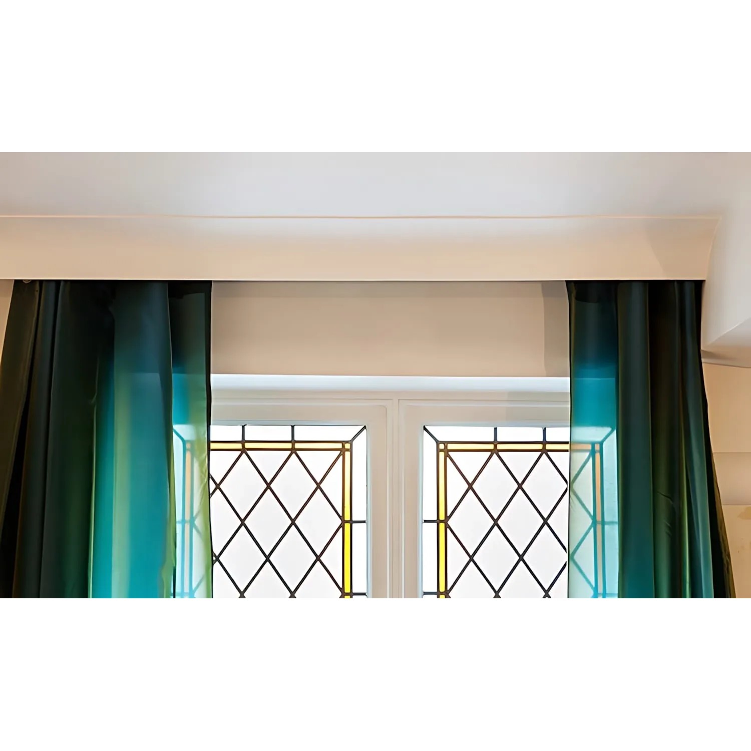 Weiße ORAC DECOR C991 Eckleiste für indirekte Beleuchtung und Gardinen, montiert über einem Fenster.