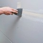 Anwendung von Knauf Uniflott Spachtelmasse auf einer Gipskartonplatte mit einem Spachtel.