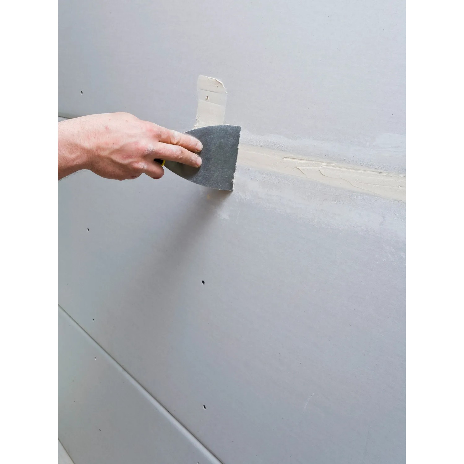 Anwendung von Knauf Uniflott Spachtelmasse auf einer Gipskartonplatte mit einem Spachtel.