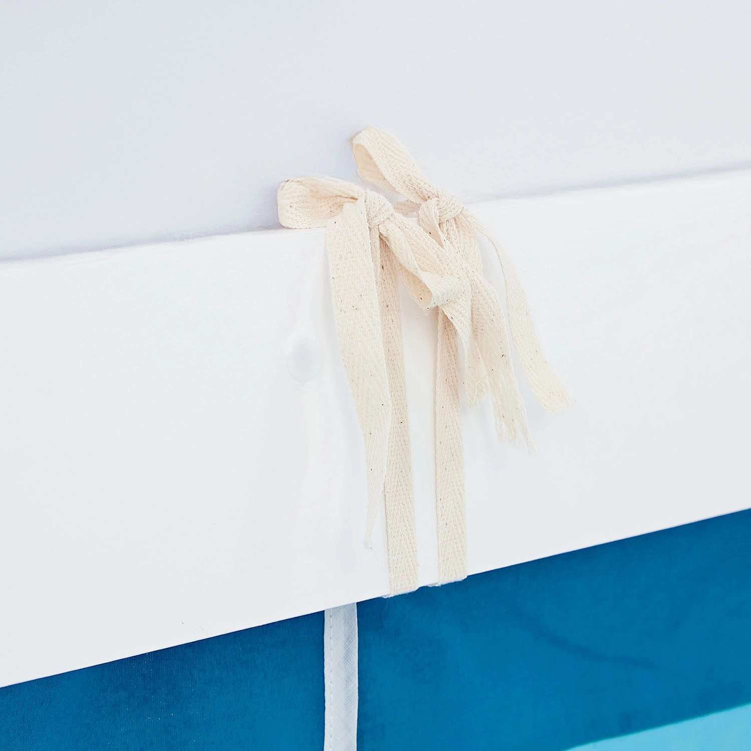 Detailansicht: Weißes Kinder Hochbett mit blauem Tunnel und Vorhang, Befestigung mit Bändern.