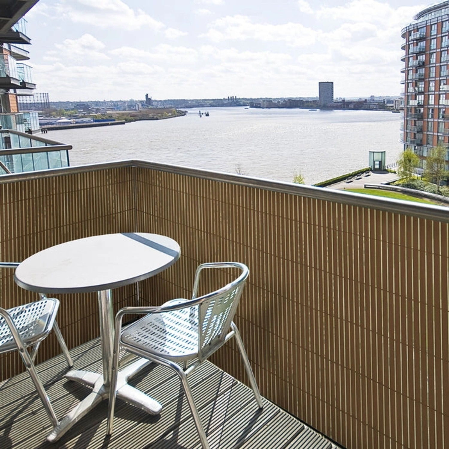 Brauner KARAT PVC Sichtschutzzaun (150x500 cm) auf Balkon mit Tisch und Stühlen.