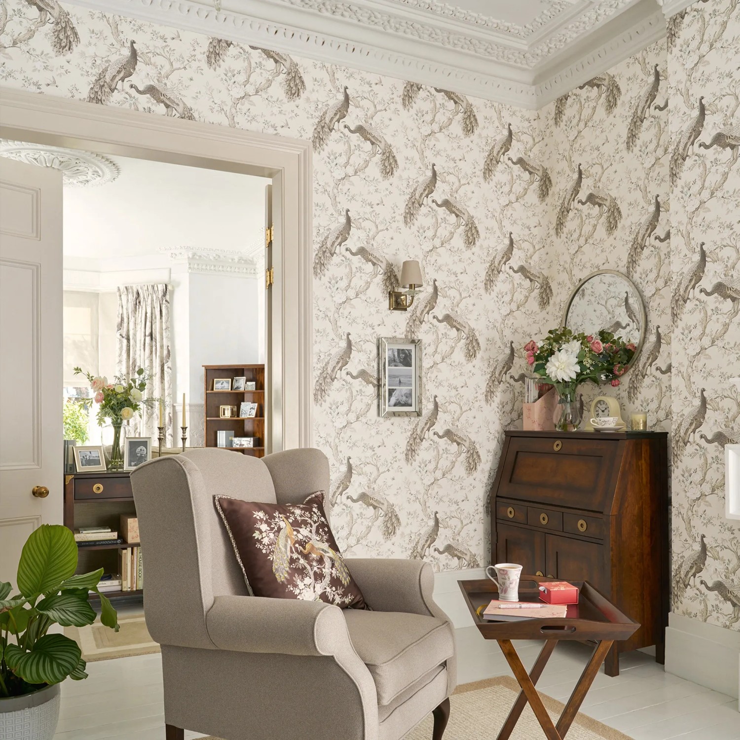 Laura Ashley Vliestapete Belvedere Soft Truffle im Wohnraum mit Pfauenmuster.