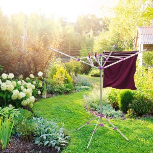 Silber-lila Relaxdays Wäschespinne mit Standfuß im grünen Garten. Klappbarer Wäscheständer aus Aluminium für 19,2 m Leine.