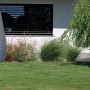 Arves Regenwassertank Drop 410 l in Granit-Optik im Garten vor Hauswand.