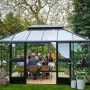 Juliana Gewächshaus Grand Oase 13 in Anthrazit (13 m²) mit Familie beim Essen im Garten.
