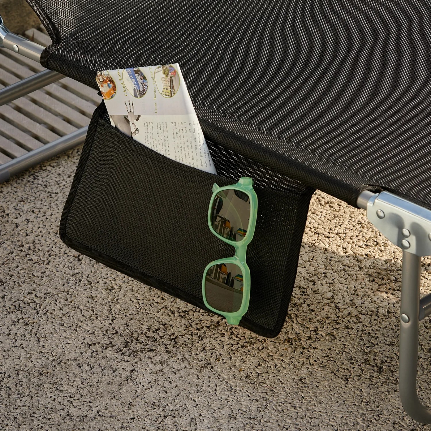 Detailaufnahme: Schwarze SoBuy Gartenliege mit Tasche für Zeitung und Sonnenbrille.