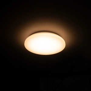 Runde, weiße Deckenleuchte (Ø 27 cm) mit warmweißem Licht an dunkler Decke.