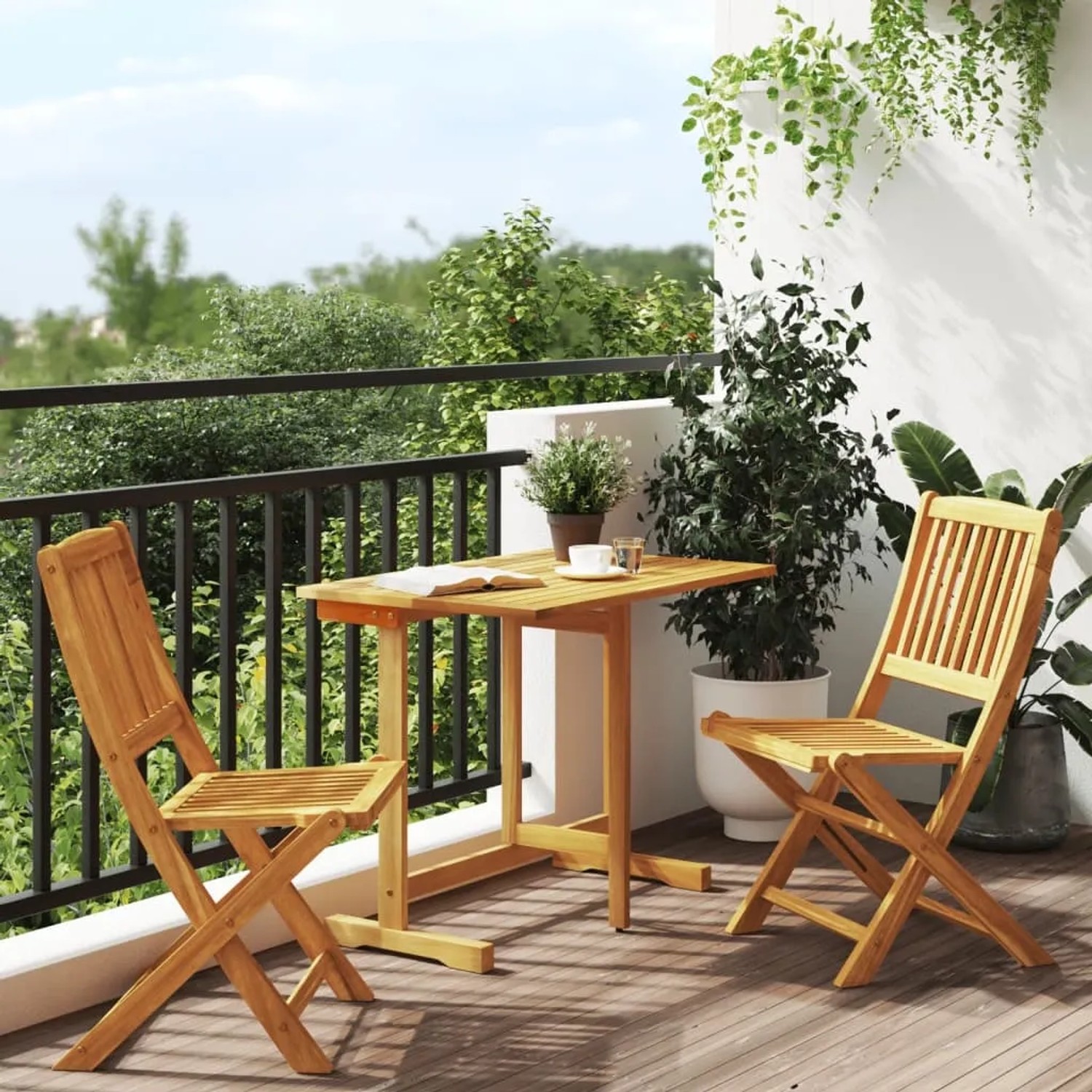Klappbare 3-tlg. Garten-Essgruppe aus Akazienholz auf Balkon mit Tisch und zwei Stühlen.