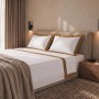 Weißes Baumwoll-Bettwäsche-Set für Doppelbett mit beiger Satin-Bordüre, elegant drapiert.