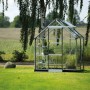 Helles Halls Gewächshaus "Icon 6 Alu" mit Glasfront und Regalen im Garten.