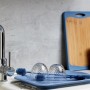 Wenko Silikon Flaschenbürste blau mit Gläsern auf Abtropfgestell in der Küche.