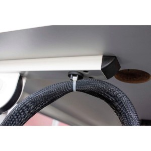 Schwarzer, flexibler EVOline Texflex Kabelschlauch mit Zipp, unter Schreibtisch für Kabelmanagement befestigt.