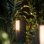 Philips Hue Turaco LED-Sockelleuchte in Anthrazit im Garten, warmweißes Licht.