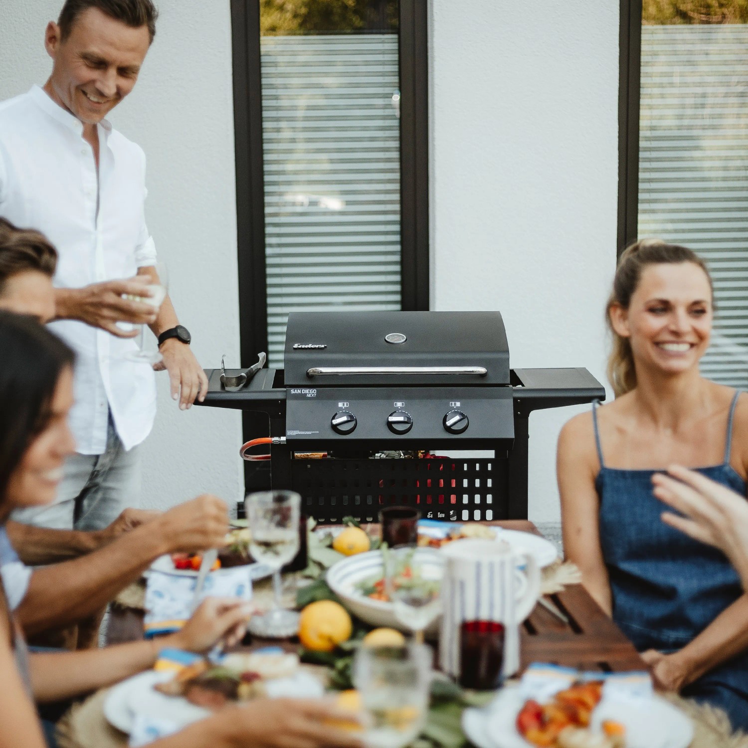 Schwarzer Enders Gasgrill San Diego Next 3 mit Seitenablagen beim Grillen mit Freunden.