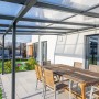 Gutta Terrassendach Premium Anthrazit mit Stegplatten, Esstisch und Gartenmöbel auf Terrasse.