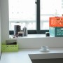 Stapelbare Klappbox-Midi in Türkis, Orange und Grün als Aufbewahrungsboxen im Regal.