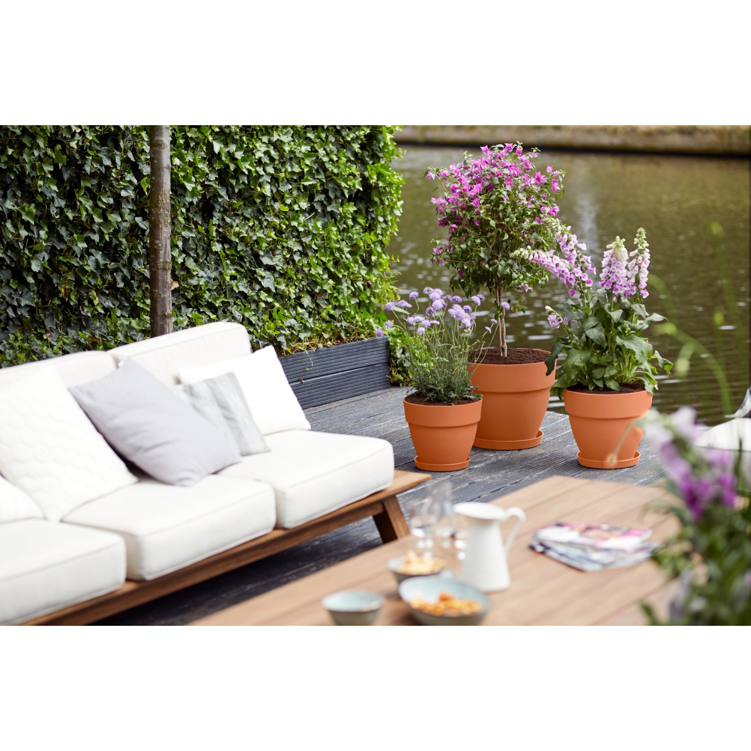 Elho Blumentopf Vibia Campana, Ø 25 cm, Terra, mit Pflanzen auf einer Terrasse.