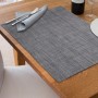 Graues, rechteckiges Tischset aus Polyester/PVC mit gewebter Struktur auf Holztisch, für Esstisch. Abwaschbar.